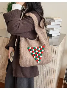 Detail of a brown knit tote bag featuring festive red and green decorative pompoms