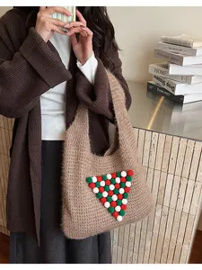 Detail of a brown knit tote bag with festive red green and white plush ball decorations