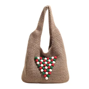 Brown knit tote bag with festive pom-poms and minimalist woven texture for winter