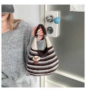 Dettaglio della borsa tote in maglia a righe con ciondolo a fungo 3D e tessuto tramato
