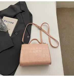Détail d'un sac à main rose en simili cuir de crocodile sur un blazer de mode élégant