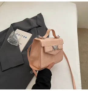 Détail d'un sac à main rose clair à motif crocodile avec serrure cœur et rabat nœud