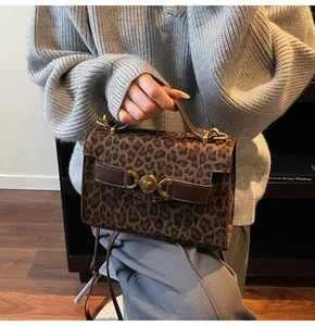Détail du sac à main léopard avec boucle en forme de cœur dorée et bordure en cuir