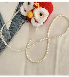 Detail of handcrafted red crochet lion bag featuring an elegant long pearl bead strap