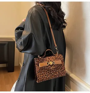 Sac bandoulière à imprimé léopard avec fermoir cœur doré porté par un mannequin