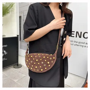 Detail view of brown suede crescent bag with gold rivets and metallic eyelets decoration