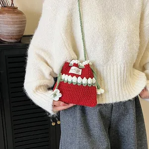 Bolso saco de ganchillo rojo hecho a mano con detalles de flores blancas y correa verde