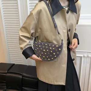 Close-up of a vintage crescent bag with gold metal studs and suede finish for women