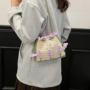 Bolso tipo cubo tejido con flores de lavanda y correa verde mostrado por una modelo