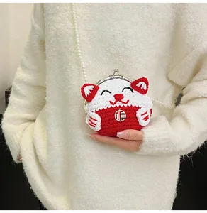 Macro shot of a red and white knitted Maneki Neko mini bag with pearl chain and lucky charm