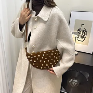 Detail of a brown suede crescent bag with gold studs on a wool coat outfit