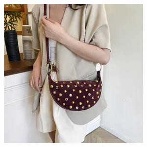 Detail of burgundy crescent bag with gold studs and rivets on suede leather material