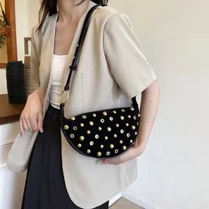 Retro black suede crescent bag with gold rivets and hollow metal eyelets on a model