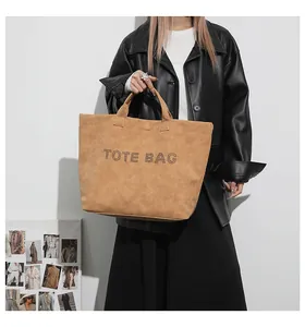 Fashionable camel suede tote bag with TOTE BAG print shown with a stylish leather jacket