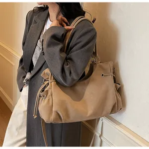 Detalle del bolso tote de ante caqui con cordón lateral y tejido suave de gran textura