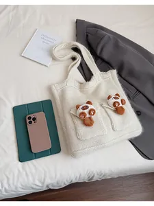 Dettaglio della borsa in maglia crema con trama spessa e graziosi ciondoli peluche