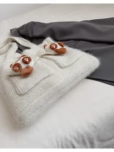 Dettaglio della borsa tote in maglia bianca con ciondoli a zampa di gatto in morbido peluche