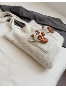 Dettaglio della borsa in maglia crema con trama morbida e decorazioni a cucciolo