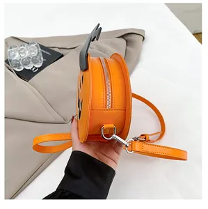 Side view of pumpkin crossbody bag with silver zipper and orange faux leather details