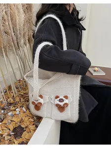 Dettaglio di simpatiche toppe di gatto in peluche 3D su una borsa tote in maglia panna
