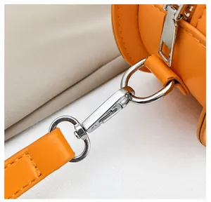 Detail of detachable silver hardware hook and strap on orange pumpkin shoulder bag