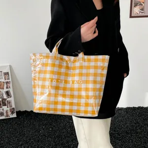 Yellow and white checkered tote bag with Tote Bag print held by a model on white background