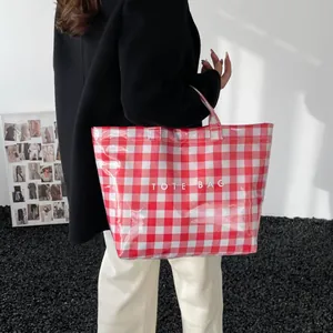 Glossy red gingham tote bag with white text print shown by model in minimalist setting