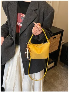 Detail einer gelben Wildlederhandtasche mit Holzperlen an grauem Wollsakko für Damen