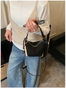 Detail der minimalistischen schwarzen Handtasche mit Holzperlenquaste und silbernem Reißverschluss