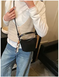 Detail der minimalistischen schwarzen Wildledertasche mit ethnischem Holzperlenanhänger