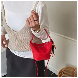 Detailansicht der roten Wildledertasche mit buntem Perlenquast und silbernem Reißverschluss