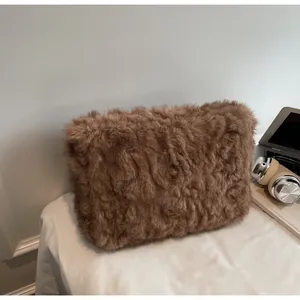 Sac à main chic en peluche marron sur un bureau, idéal pour un style d'hiver quotidien