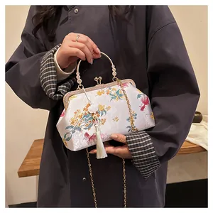 Close-up of Chinese shell bag with floral embroidery, tassels, and golden chain strap