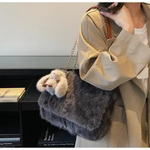 Detail of grey faux fur crossbody bag with golden chain and white rabbit pendant