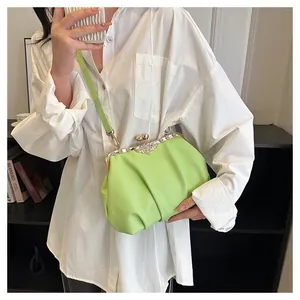 Close-up of light green pleated cloud bag with rhinestone flower clasp on white shirt