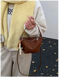 Detailansicht der braunen Wildlederoptik-Handtasche mit Holzperlen und Metallgriff