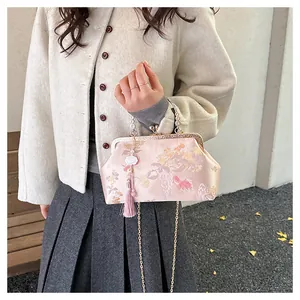Detail of pink silk cheongsam bag with floral embroidery, metal handle and tassel charm