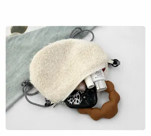 Interior space of the cream fuzzy crossbody bag showing daily essentials and lining
