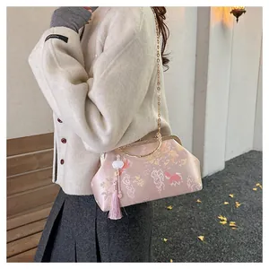 Detail of pink brocade shell bag with floral patterns, gold handles and tassel charm