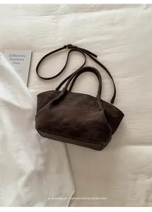 Macro shot of dark brown suede tote bag with vintage gold hardware and adjustable strap