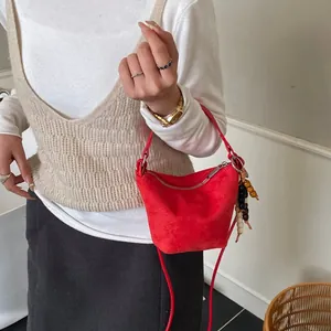 Rote Wildleder-Umhängetasche mit buntem Perlenanhänger im modischen Outfit-Look