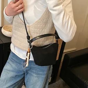 Schicke schwarze Wildleder-Eimertasche mit Perlenanhängern und vielseitigen Riemen