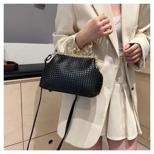 Detail of black woven shell bag featuring pearl clasp and gold rhinestone metal frame