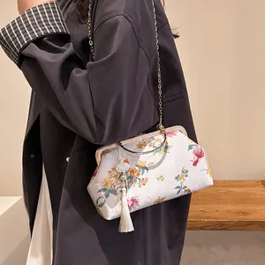 Elegant New Chinese shell bag with floral patterns, gold handles and white silk tassels