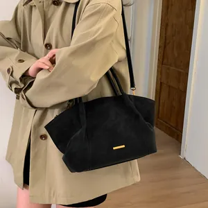Chic black suede tote bag with gold hardware and slim shoulder straps in a minimalist style