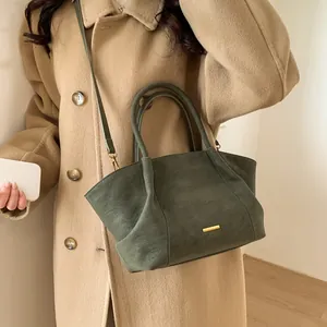 Retro dark green leather tote bag with gold buckle worn with a beige wool coat
