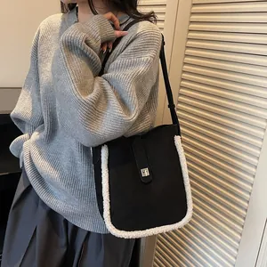 Vintage Umhängetasche in Schwarz mit weißem Lammfellbesatz über grauem Strickpullover