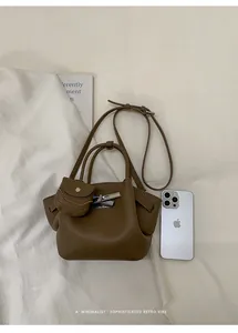 Detail of brown lychee texture leather handbag with mini charm and silver hardware