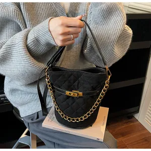 Detail of black quilted bucket bag featuring gold twist lock and chain handle