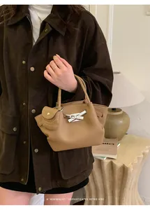 Detail of khaki lychee grain leather handbag with silver clasp and mini pouch charm